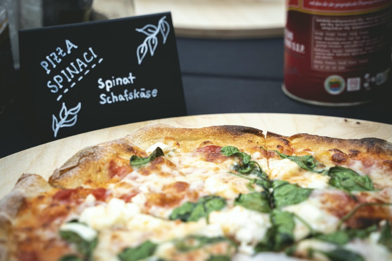 Pizza Spinaci mit Spinat und Schafskäse auf Holzbrett mit Kreideschild